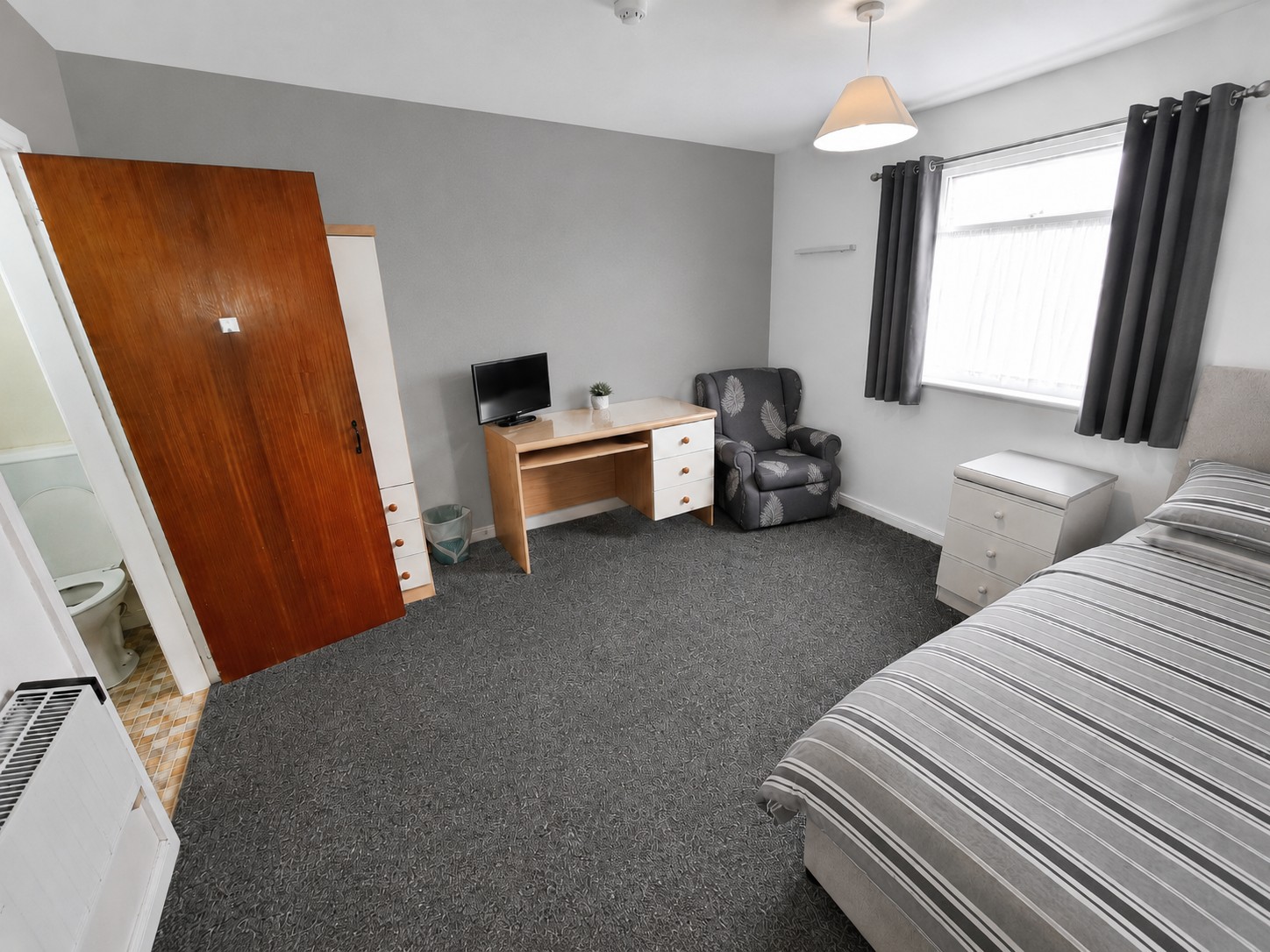 Single room at The Coach House with a bed, desk and window